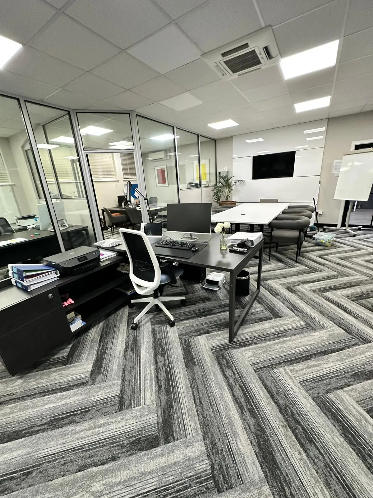 Professional office cleaning in a modern workspace with herringbone carpet, clean desks, and ergonomic chairs in Hertfordshire, Essex & London